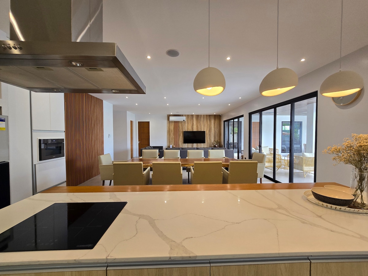 Kitchen view toward open-plan living and dining area with pendant lights
